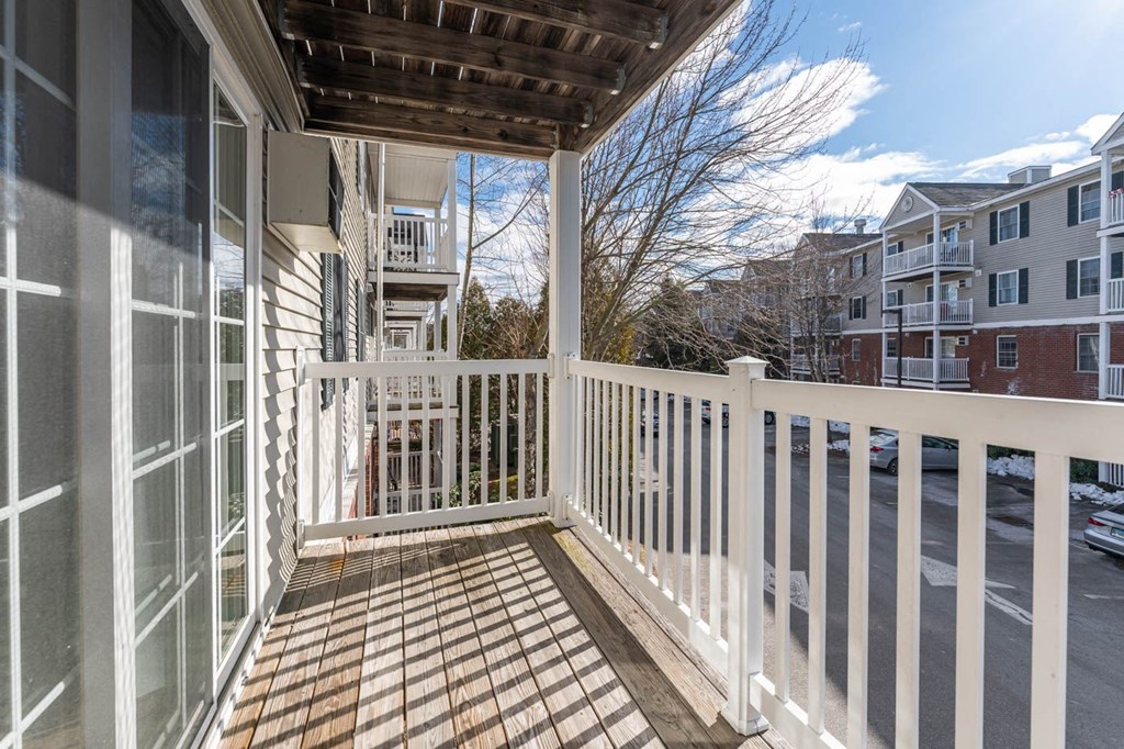 a porch with a white railing and a building in the background