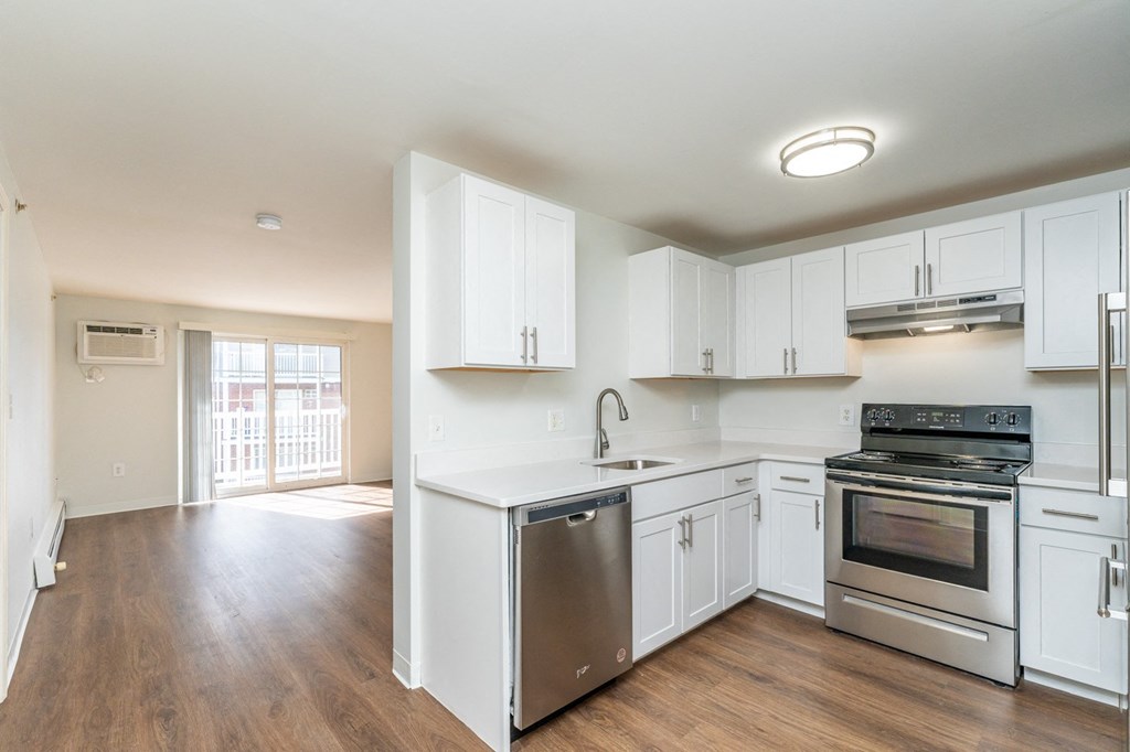 an empty kitchen with white cabinets and stainless steel appliances