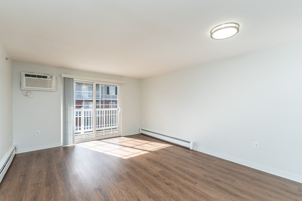 an empty living room with wood flooring and a door to a balcony
