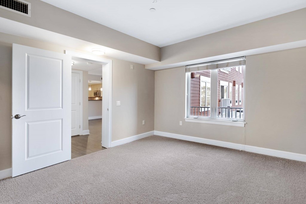 A room with a white door and a window with a view of a building outside.