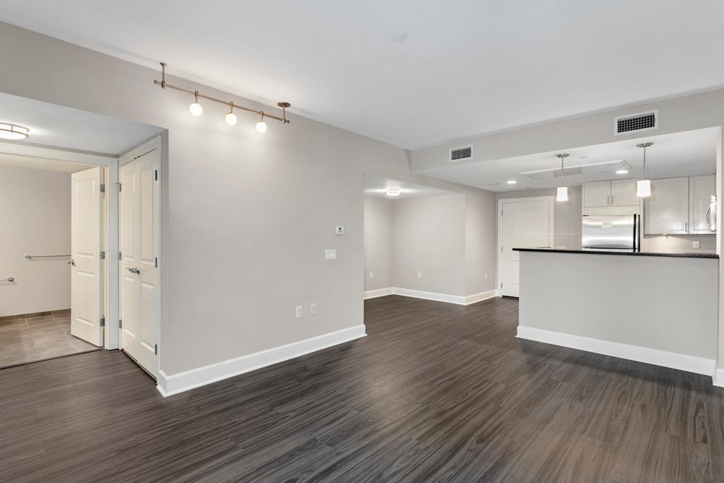 A spacious room with wood flooring and a bar area.