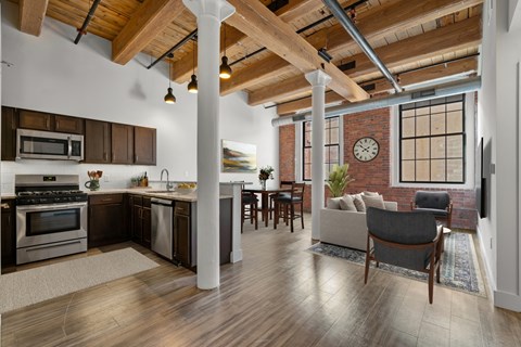 A modern kitchen with wooden floors and a brick wall.