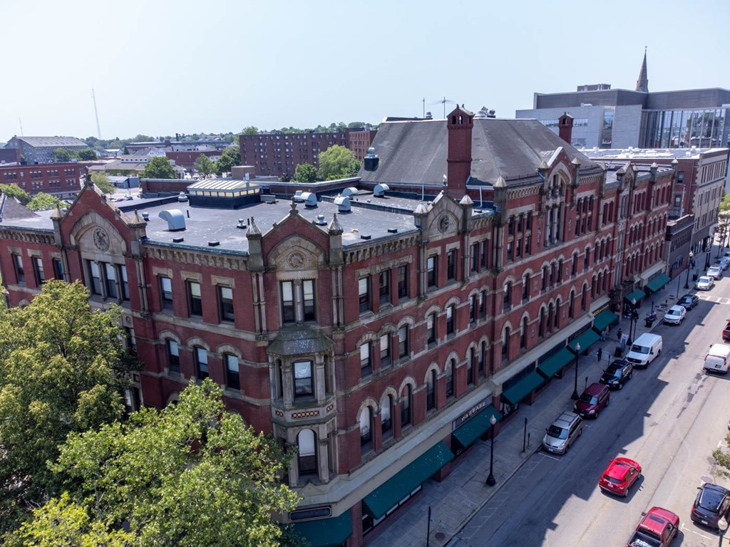 A large red brick building with a green awning sits on a street corner.