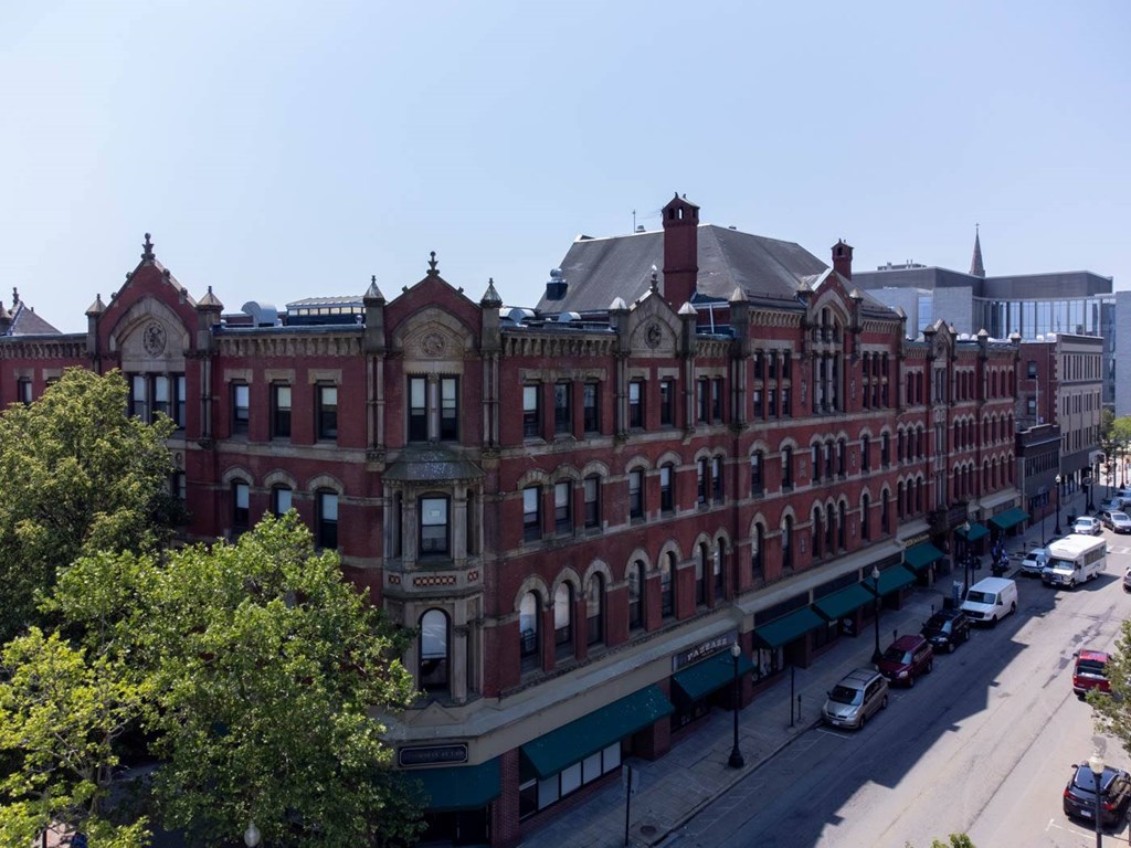 A large red brick building with a clock tower sits on a street corner.