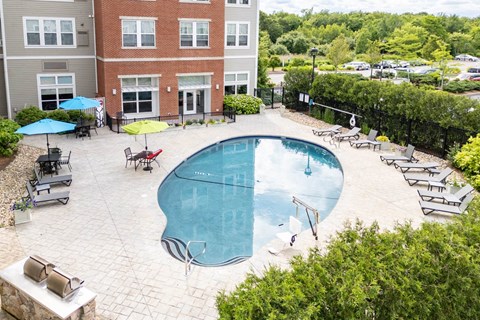 a swimming pool with chairs and umbrellas in front of a building