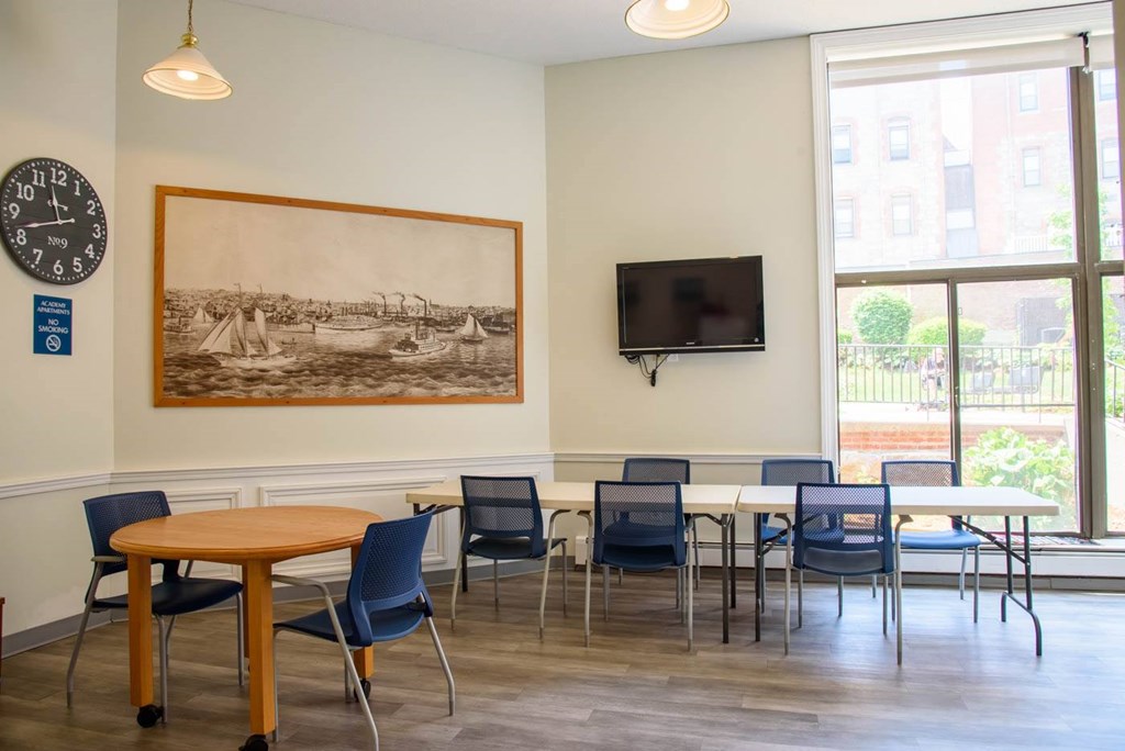 A room with a table, chairs and a painting on the wall.