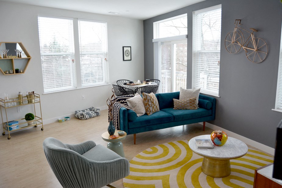 a living room with a blue couch and yellow and gray rug