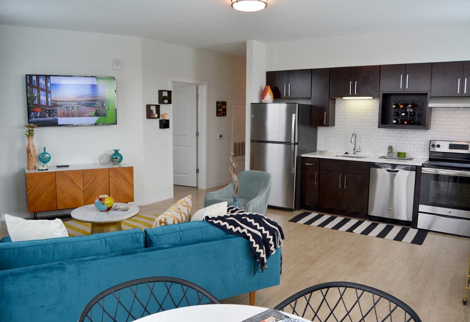 a kitchen and living room with a blue couch and black and white striped rug