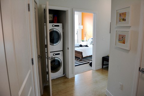 a laundry room with a washer and dryer and a bedroom in the background