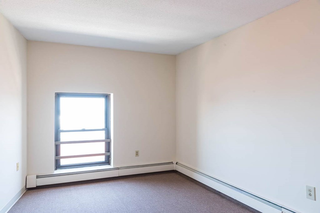 A room with a window and carpeted floor.