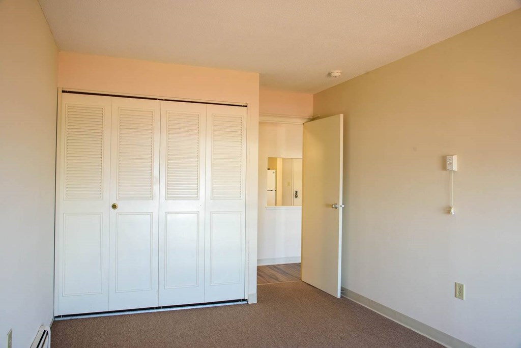A room with a white door and carpeted floor.