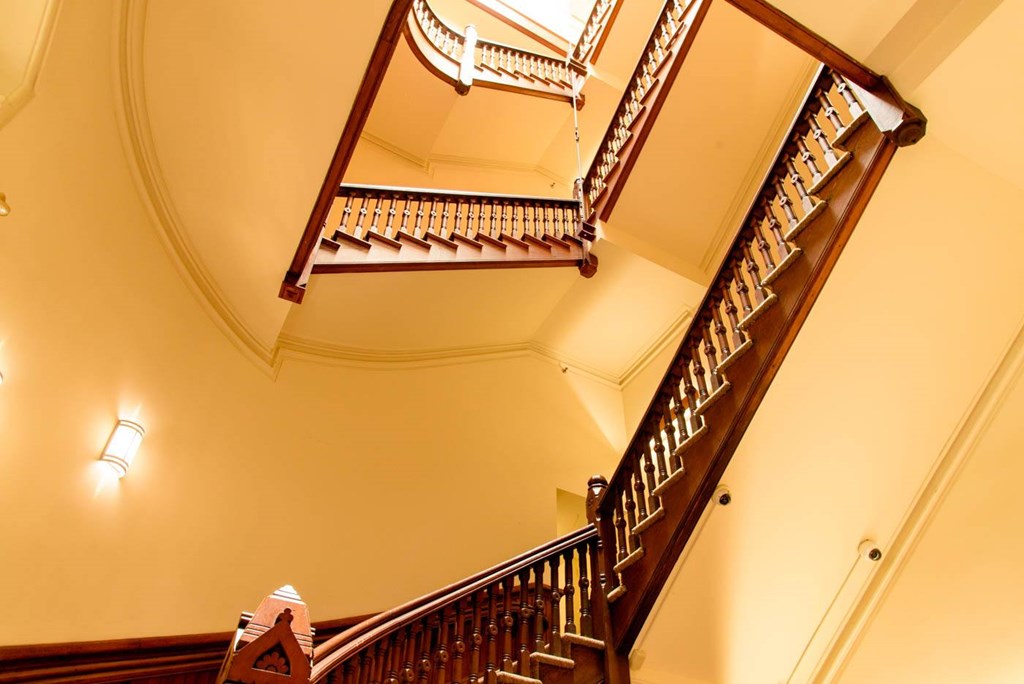 A staircase with a wooden handrail and a light on the wall.
