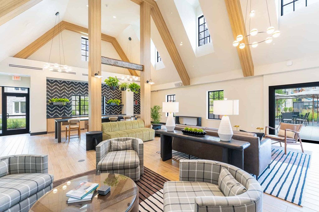 Light-filled resident lounge at The Devon at Weiss Farm in Stoneham, MA featuring vaulted ceilings and modern seating areas.