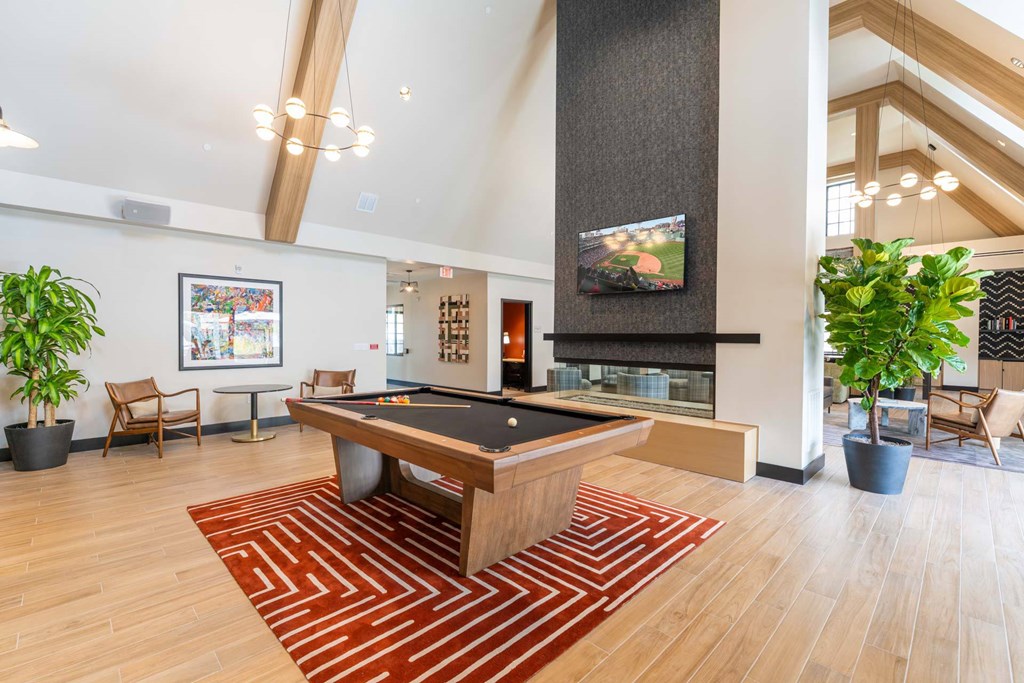 Game room at The Devon at Weiss Farm apartments in Stoneham, MA with billiards table, TV and modern fireplace.