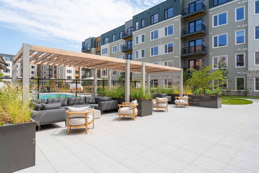 Outdoor seating under a pergola overlooking the pool at The Devon at Weiss Farm apartments in Stoneham, MA.