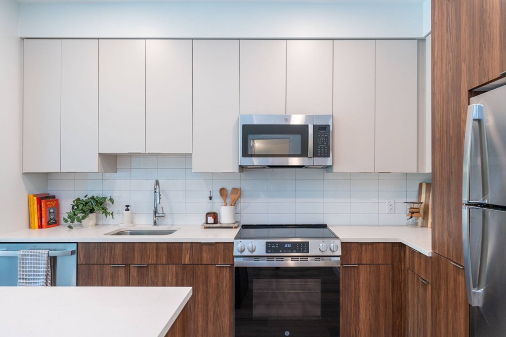Sleek kitchen at The Devon at Weiss Farm in Stoneham, MA with quartz countertops, wood cabinetry and stainless appliances.