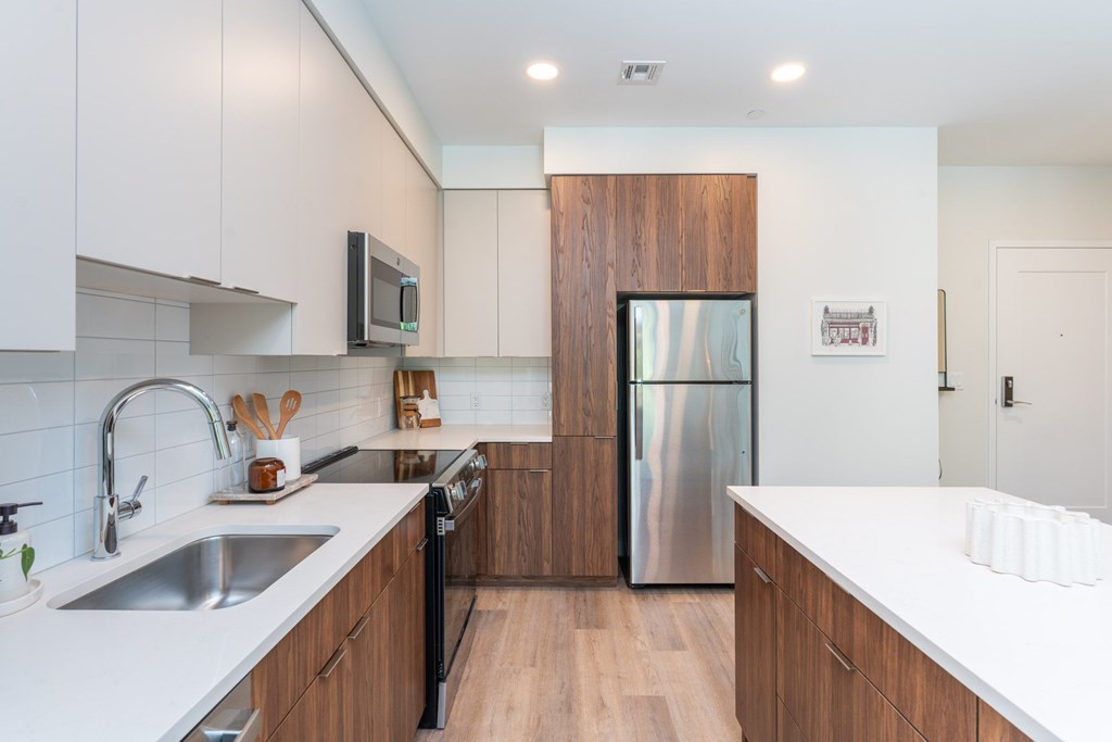 Modern kitchen with island, quartz counters and stainless appliances at The Devon at Weiss Farm in Stoneham, MA.