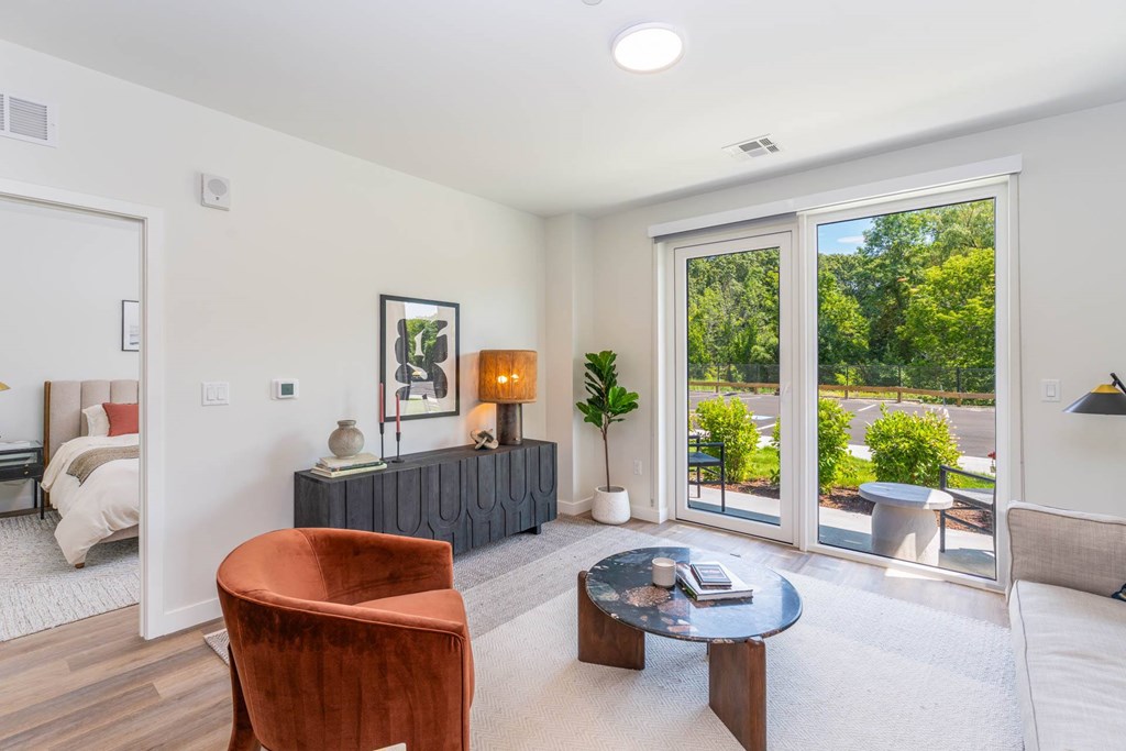 Bright living room at The Devon at Weiss Farm apartments in Stoneham, MA featuring sliding glass doors and modern furnishings.