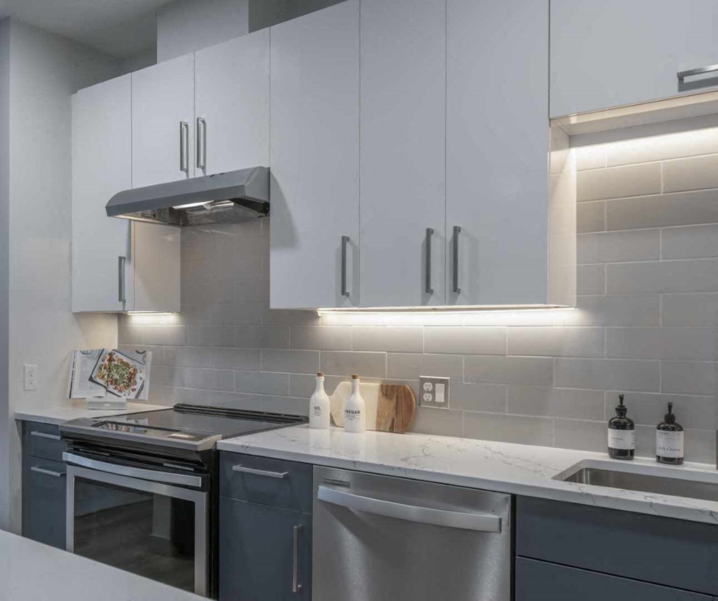 a kitchen with white cabinets and gray countertops