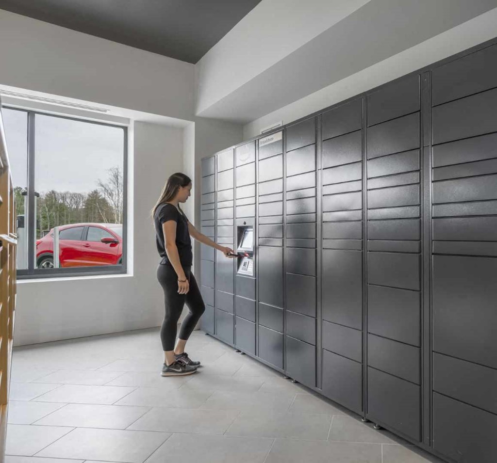 a woman in a black shirt and black leggings opens a drawer in a gray locker