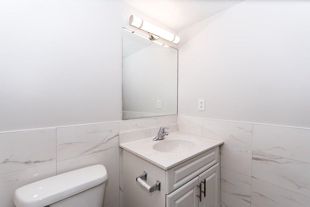 a bathroom with white tiles and a white sink and toilet