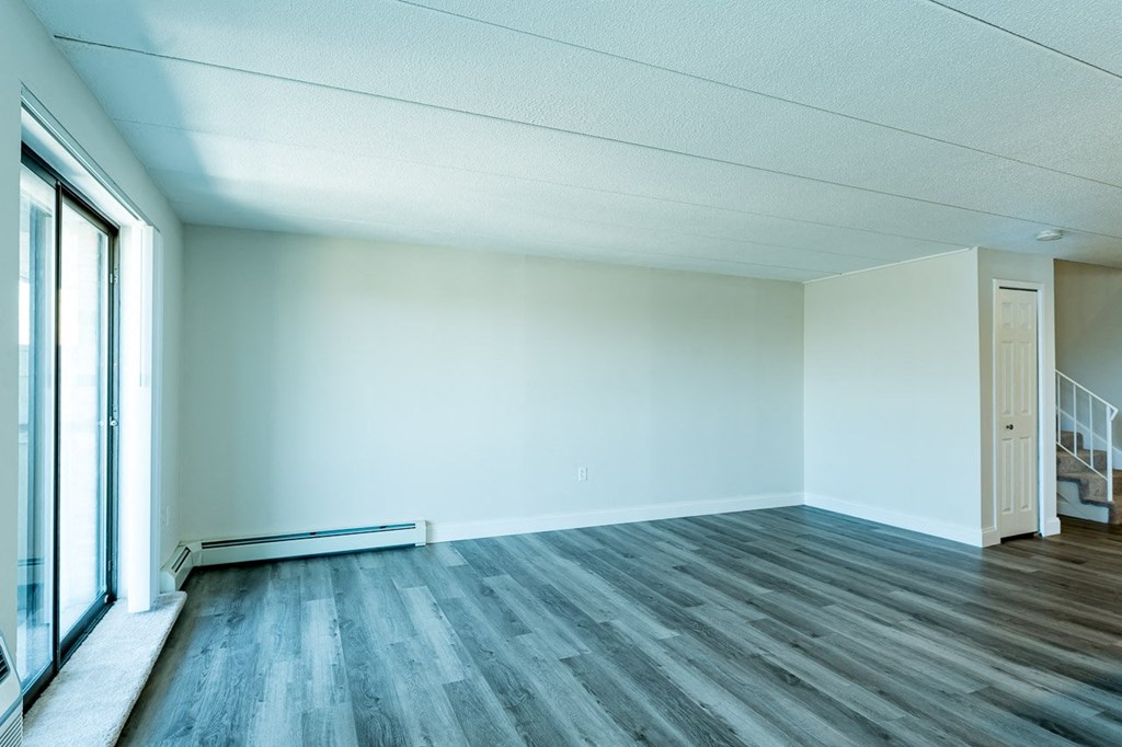 an empty room with a large window and hardwood floors