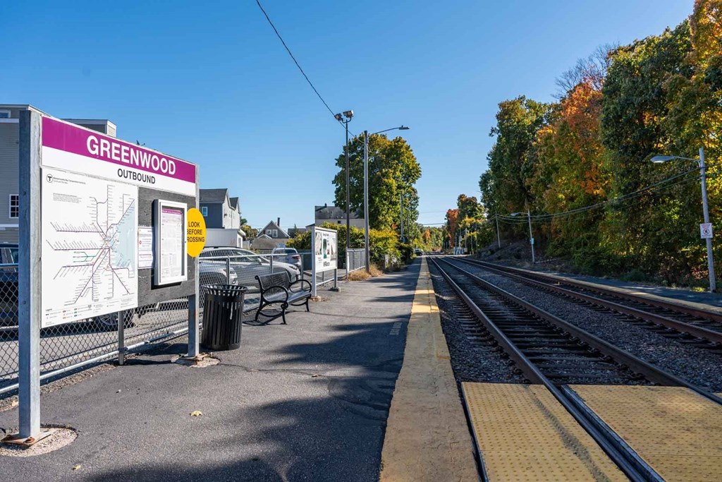 A train station named Greenwood Outbound is shown with a sign, a bench, and a trash can.