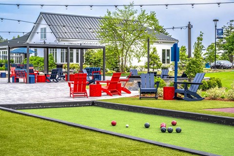 A lawn bowling green with balls and bowls in the foreground and a house in the background.