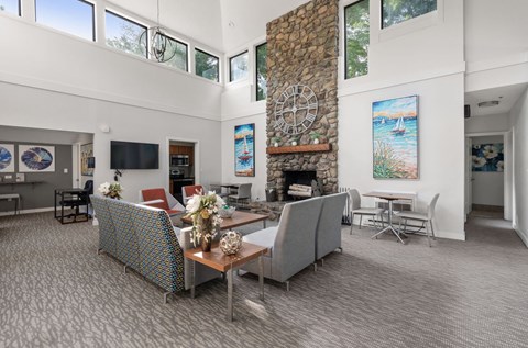 A living room with a stone fireplace and a painting of a beach scene on the wall.
