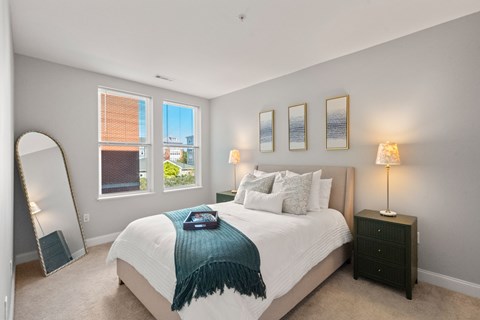 A bedroom with a large bed and a window overlooking a cityscape.