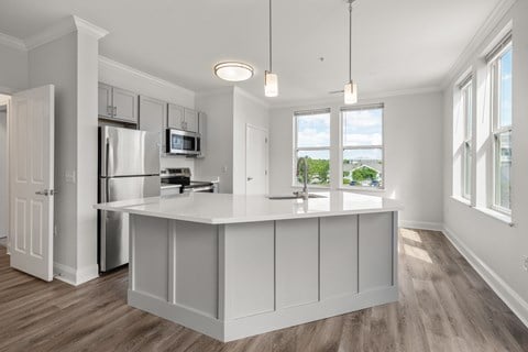 A kitchen with white cabinets and a wooden floor.