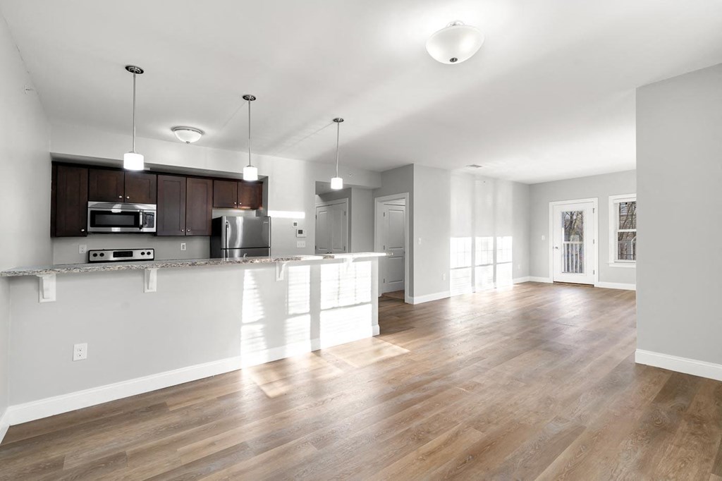 Ashland woods apartments in massachusetts with open floor plans, kitchen in background and living room with large windows.