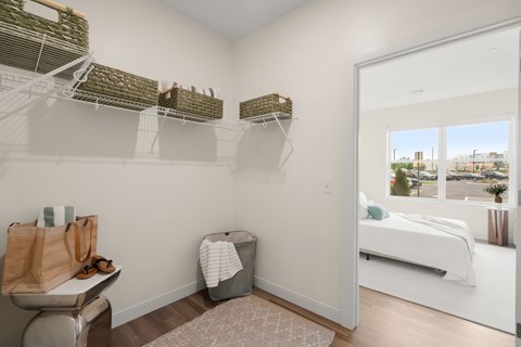A bedroom with a white bed and a window overlooking a cityscape.