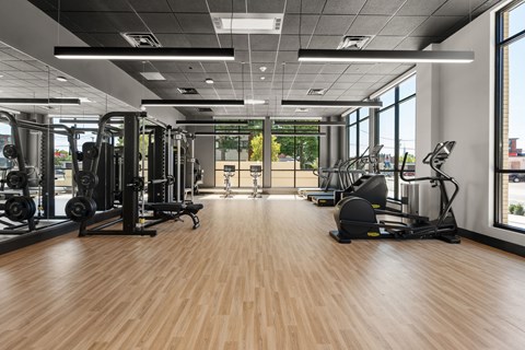 A gym with a variety of equipment including treadmills, weights, and exercise machines.