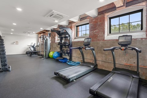 A gym with treadmills, weights, and exercise equipment.