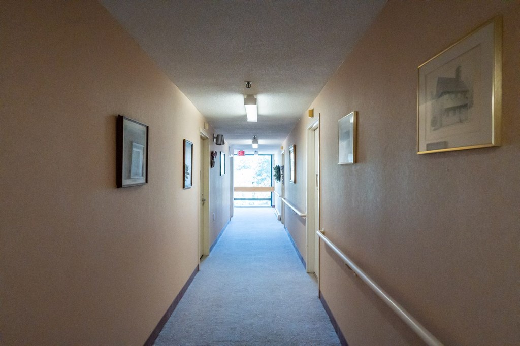 a long hallway with pictures on the wall and a carpeted floor