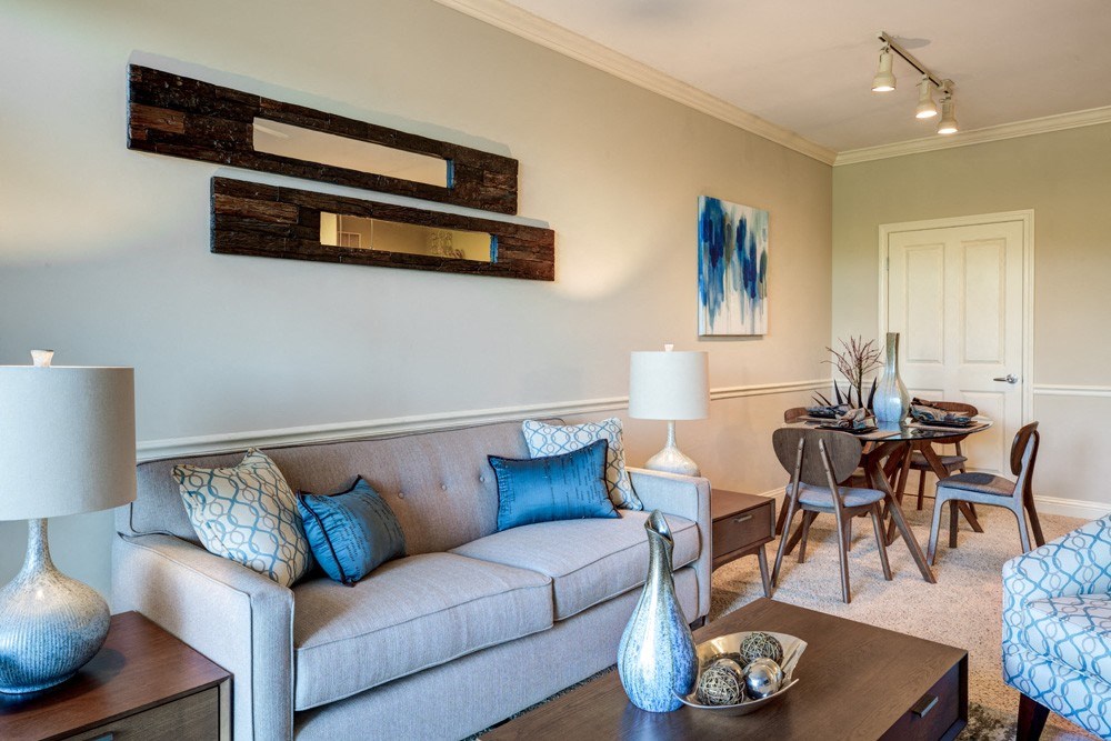 A living room with a grey couch, a coffee table, and a dining table.