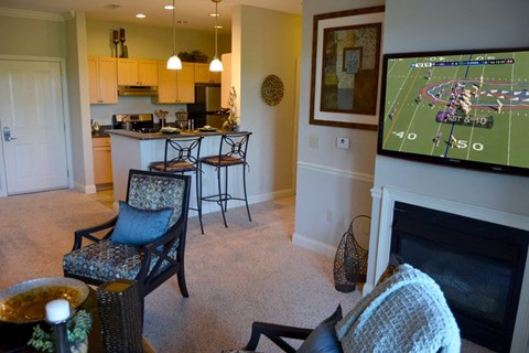 A living room with a fireplace and a television showing a football game.