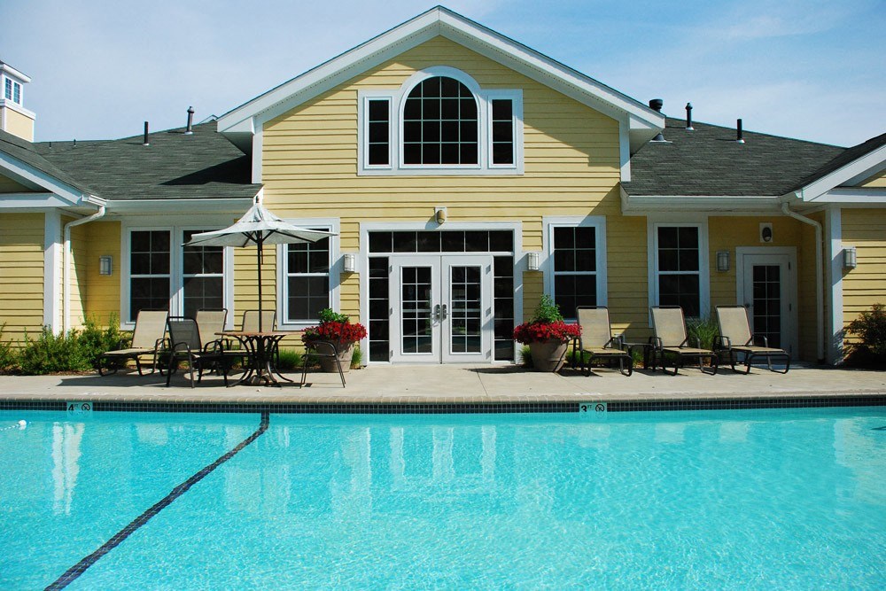 A yellow house with a pool in front.