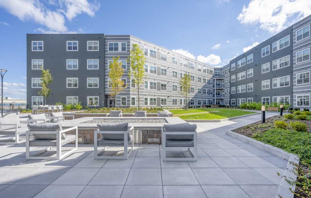 a courtyard with a fire pit and a large building in the background