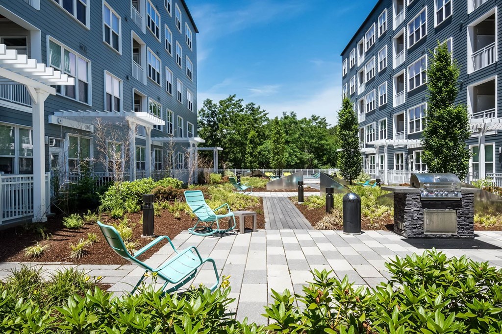 a patio with a fire pit and lounge chairs in front of a building