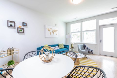 a dining room with a white table and chairs and a blue couch in the background