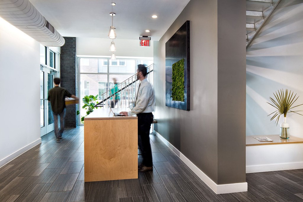 a man in a white shirt and black pants stands at the front desk of an office
