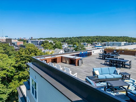 a rooftop deck with furniture and a view of the city
