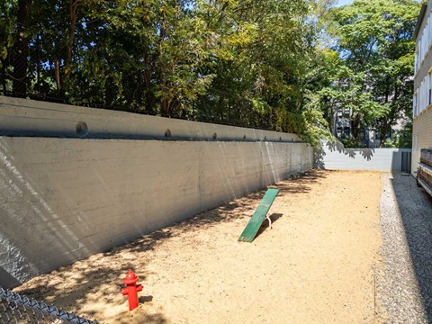 a red fire hydrant sitting in the sand next to a fence