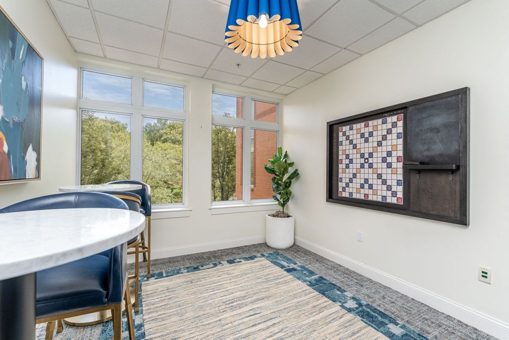a room with a table and chairs and a bulletin board with a quilt on the wall