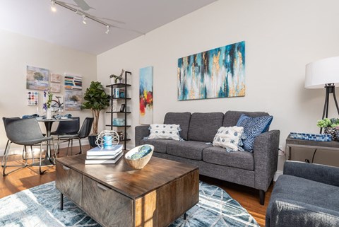 A living room with a grey couch, a wooden coffee table, and a painting on the wall.