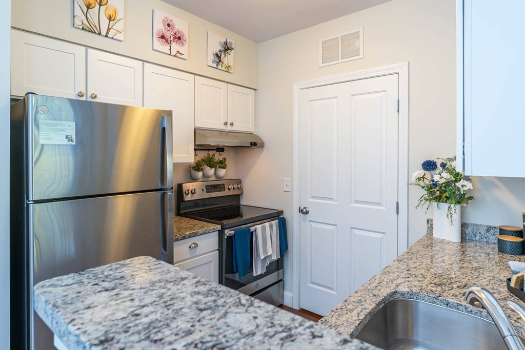 Parkside Commons white cabinetry kitchen with a granite countertop and stainless steel appliances.