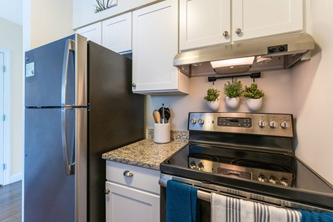 A black refrigerator is next to a stove in a kitchen.