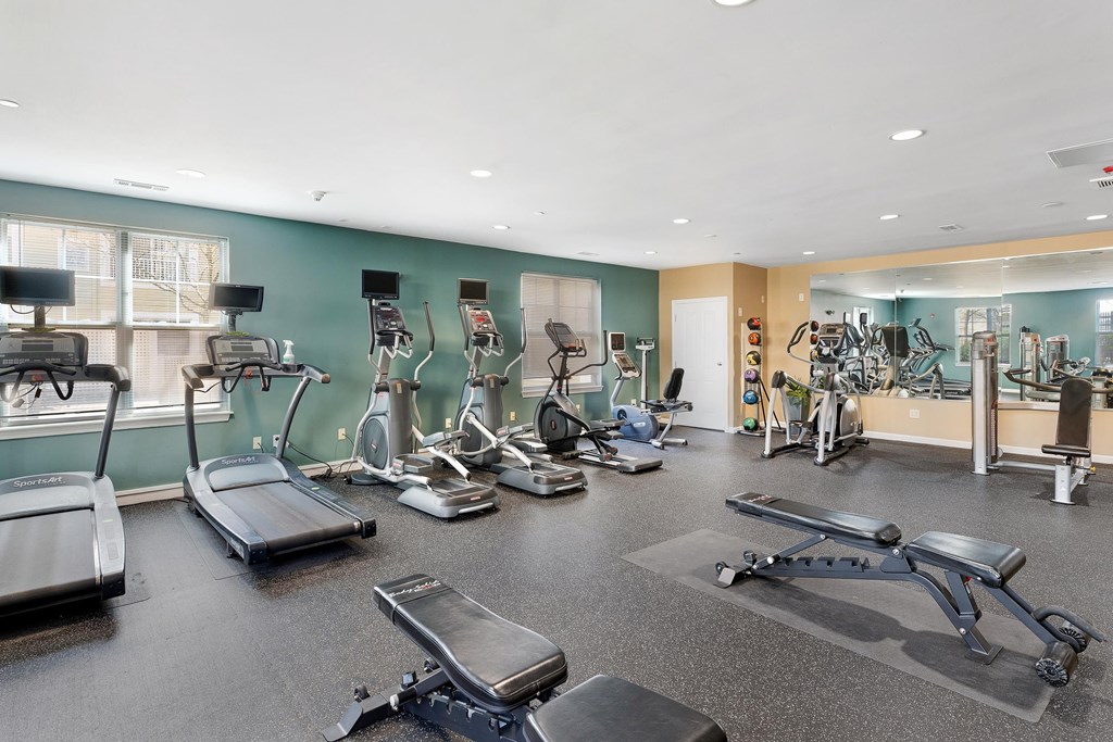 A gym with treadmills, exercise bikes, and other equipment at Parkside Commons